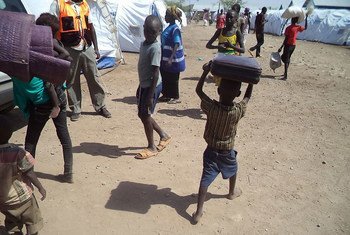 A barefooted little boy who has just arrived in Kakuma refugee camp, north-western Kenya, from South Sudan, runs with a suitcase on his head, trying to keep up with registration procedures.