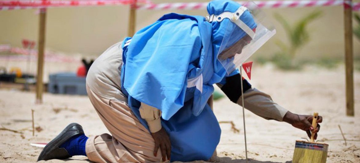 A female member of an Explosive Ordnance Disposal team brushes sand off of a mortar shell during a demonstration held by UNMAS in Mogadishu, Somalia.