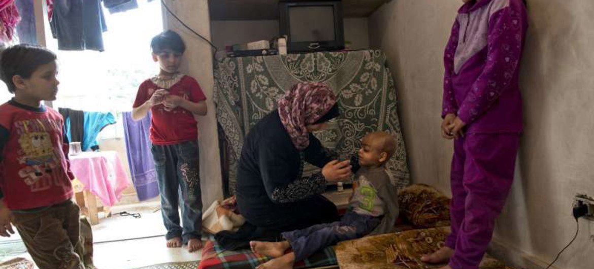 لبنان، أم سورية تعطي الماء لإبنها الذي يعاني من مع مرض السرطان. صورة من مفوضية شؤون اللاجئين