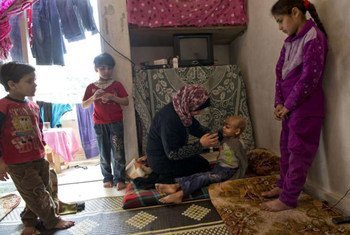 A Syrian mother gives water to her son in Lebanon, who is desperately ill with cancer. The influx of so many refugees has severely stretched health services.