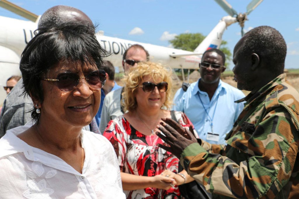 Une dignitaire féminine serre la main d'un homme en uniforme militaire devant un avion de ONU sur un aérodrome.
