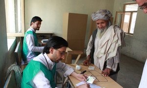 Electoral workers in Afghanistan (left) assisting a voter in the 14 June 2014 second round run-off in the country's presidential elections.
