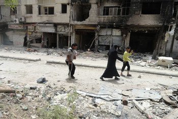 Palestinians walk home amid the devastation inside Yarmouk refugee camp in Syria, where restrictions on aid deliveries continue to severly impact the lives of the people (June 2014).