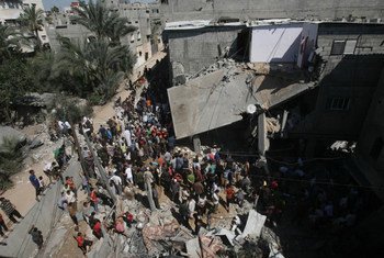 A large crowd gathers in front of a home that was destroyed during Israeli air strikes in the city of Khan Yunis in the southern Gaza Strip (8 July 2014). Repeated air strikes have destroyed many homes during the recent escalation of violence.