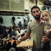 Onboard an Italian ship, a Syrian father holds his one-year-old son as they wait to be checked by doctors. They were rescued in the middle of the Mediterranean.