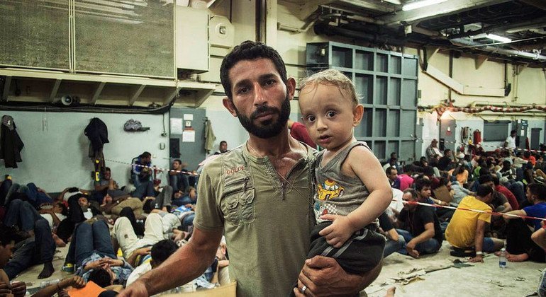 A bordo de un barco italiano un padre sirio sujeta a su hijo de un año, tras ser rescatados en medio del Mediterráneo. Foto de archivo: ACNUR/A. DAmato