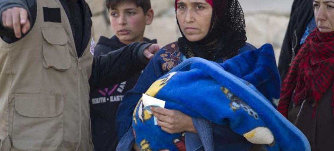 A Syrian refugee mother waits in line with her child to collect aid in Arsal, Lebanon.