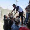 Un membre du personnel de UNFPA remet une boîte en carton à une femme vêtue d'une robe noire et d'un foulard lors d'une distribution d'aide en Irak.