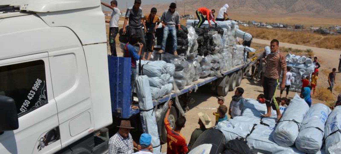 Workers unload trucks laden with hundreds of tents for families displaced by the recent fighting in Iraq.