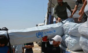 Workers unload trucks laden with hundreds of tents for families displaced by recent fighting in Iraq.