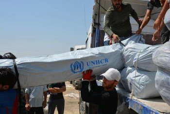 Workers unload trucks laden with hundreds of tents for families displaced by recent fighting in Iraq.