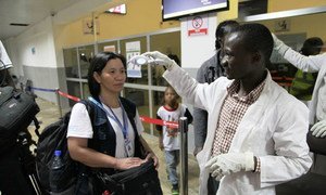 Un employé de l'OMS vérifie la température d'une voyageuse à l'aéroport de Lugin, à Freetown, en Sierra Leone, en septembre 2014. Photo OMS Sierra Leone