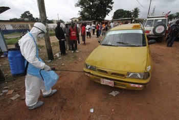 Un travailleur sanitaire désinfecte un taxi devant un centre de traitement de l'Ébola au Libéria.