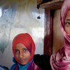 Two displaced girls stand in front of the classroom where their family has been living in Aden, Yemen (September 2012).