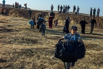 A Syrian boy, followed by his family runs with his bag moments after crossing the border into Jordan.