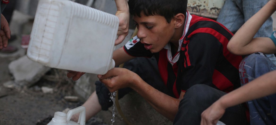 A boy drinks the remaining water in his jerrycan while waiting with other children in a queue for safe water in the town of Douma in the East Ghouta area of Rural Damascus, Syria.