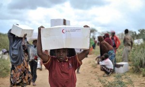 A young boy carries away a box of food from a distribution centre in Afgoye, Somalia.