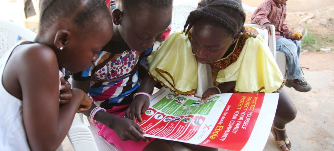 Girls in the city of Voinjama look at a poster that displays information and illustrations about how to prevent the spread of Ebola.