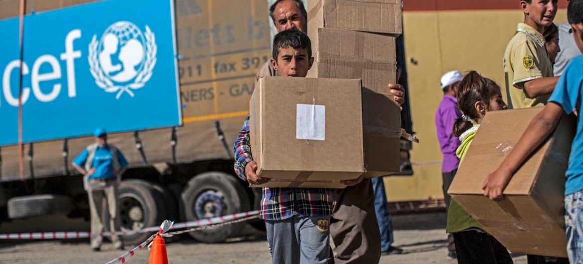 Displaced persons collect packages containing winter clothes and boots at a UNICEF distribution centre in Mangesh, a village in northern Iraq.