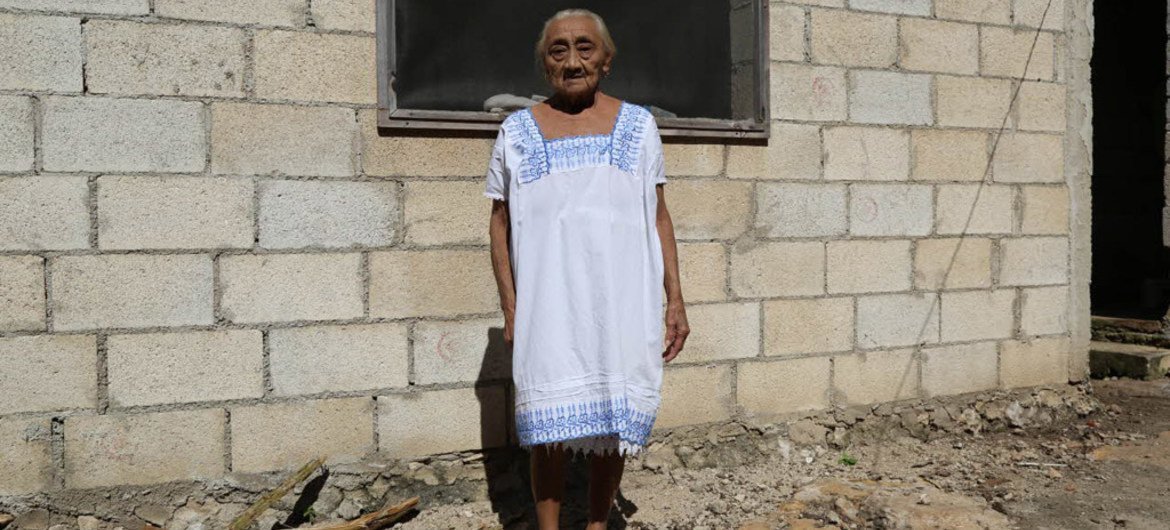 An old person posing in front of her house in Chagas, Mexico, where long-lasting impregnated curtains were installed in order to keep the house free of the triamatone bugs.