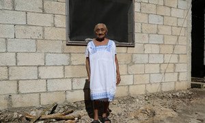 An old person posing in front of her house in Chagas, Mexico, where long-lasting impregnated curtains were installed in order to keep the house free of the triamatone bugs.
