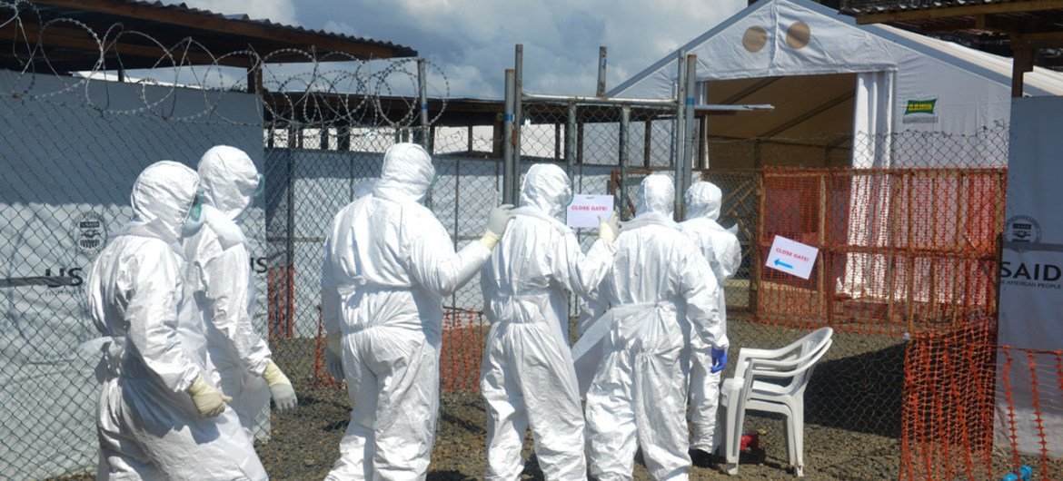 Health workers wearing personal protective equipment (PPE) walk in single file to a gate leading out of the green (safe) zone, at a newly built Ebola treatment unit (ETU) in Monrovia, Liberia.