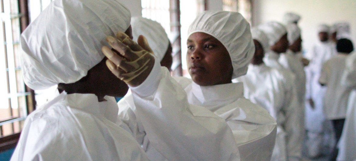 A health worker wearing personal protective equipment helps a colleague adjusts her cap during a training session in Sierra Leone.