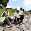 Working alongside her male team member, a female employee checks the quality of work at a dam under construction in Sri Lanka.