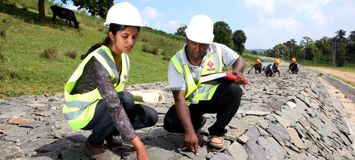 Working alongside her male team member, a female employee checks the quality of work at a dam under construction in Sri Lanka.
