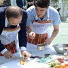 Secretary-General Ban Ki-moon (left) samples food prepared on fuel-efficient cook stoves at the UN Climate Change Conference in Lima, Peru.