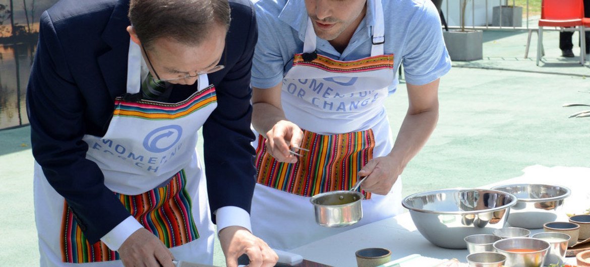 Secretary-General Ban Ki-moon (left) samples food prepared on fuel-efficient cook stoves at the UN Climate Change Conference in Lima, Peru.