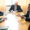 A group of professionals in business attire are seated around a conference table, engaged in a serious discussion.