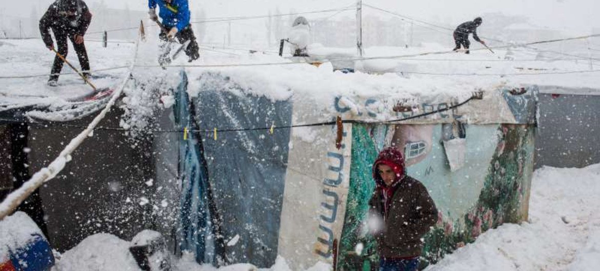 叙利亚难民在黎巴嫩贝卡谷地移除居住帐篷顶上的积雪。难民署图片/A. McConnell
