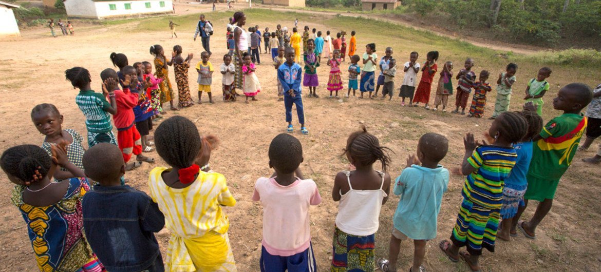 In Ebola-affected Guinea, children, supervised by an adult, play outdoors in a large circle in the village of Meliandou in Guéckédou Prefecture, Nzérékoré Region.