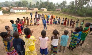 En Guinée, qui a été très touchée par Ebola, des enfants, encadrés par un adulte, jouent dans le village de Meliandou. Photo : UNICEF/Mark Naftalin