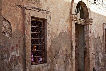 Une fille regarde à travers la fenêtre de sa maison à Benghazi, en Libye.