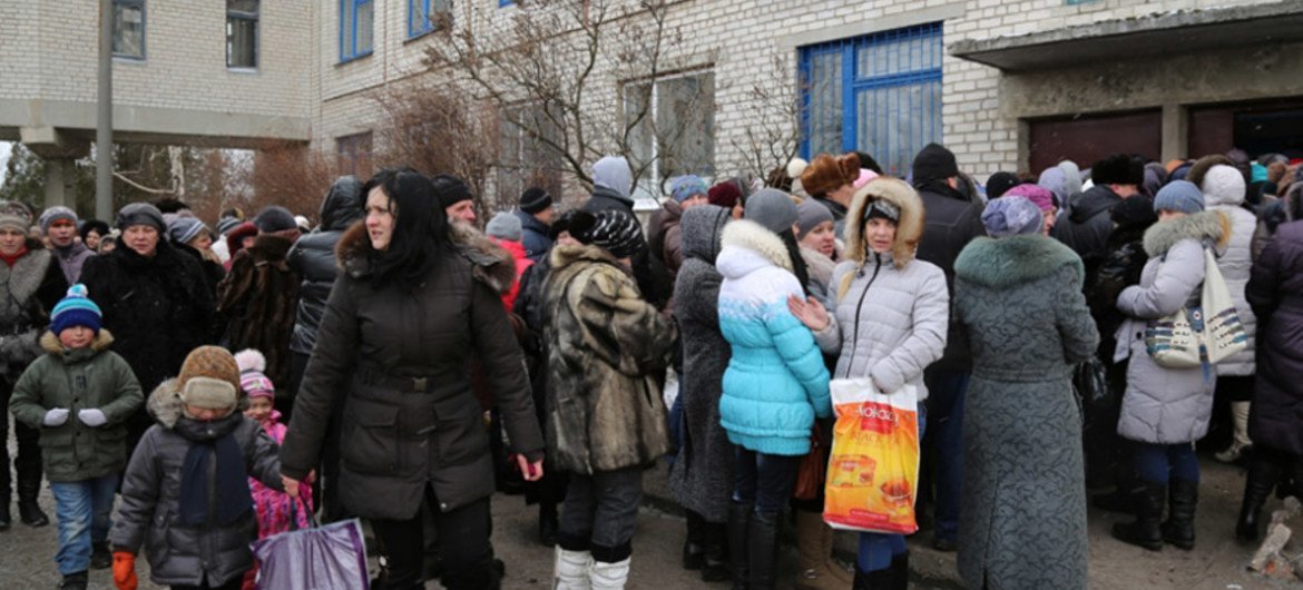 Des familles déplacées et des personnes âgées en Ukraine font la queue pour obtenir des bons alimentaires du PAM. 