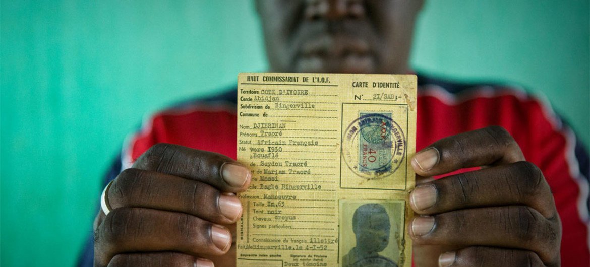 A man identified as Oumar, who was at risk of statelessness, holds his father's identity card from French colonial times.