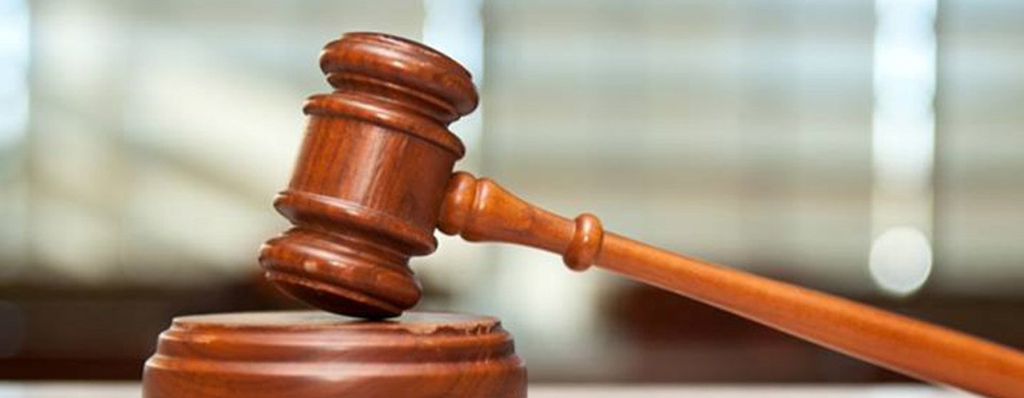 Un maillet de juge en bois posé sur son socle, sur un bureau.