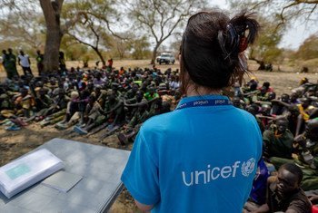 A UNICEF worker stands in front of a group of children undergoing release from the SSDA Cobra Faction armed group, in Pibor, Jonglei State on 10 February 2015.