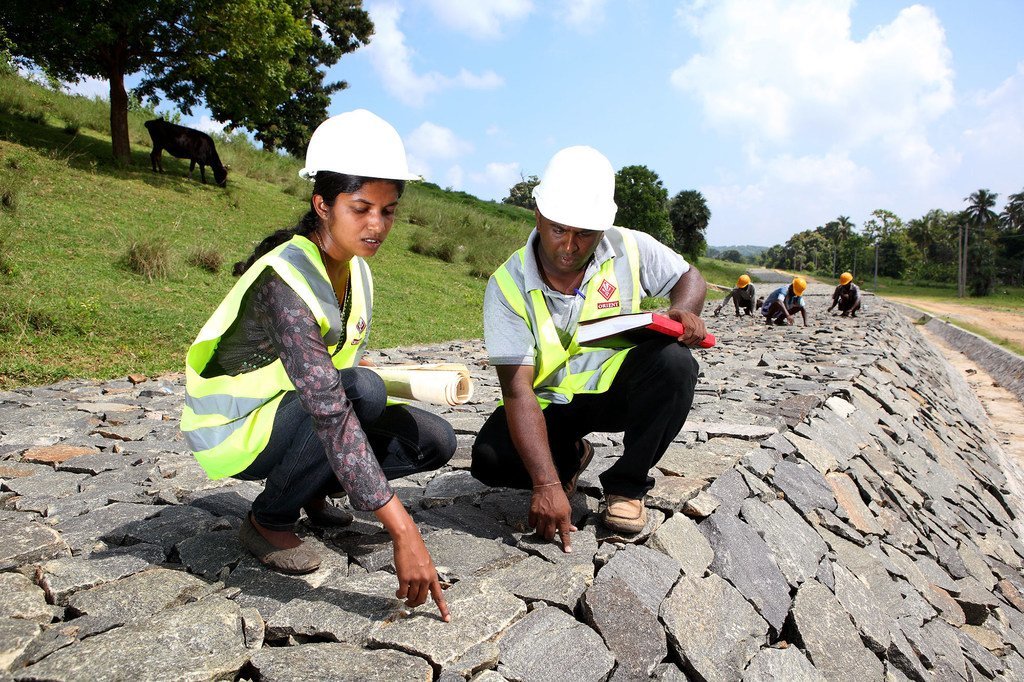 Working alongside her male team member, a woman employee checks the quality of work at a dam under construction in Sri Lanka.
