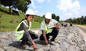 Working alongside her male team member, a woman employee checks the quality of work at a dam under construction in Sri Lanka.