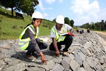 Working alongside her male team member, a woman employee checks the quality of work at a dam under construction in Sri Lanka.