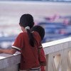 两名儿童站在老挝一个移民办公室的阳台上。联合国儿童基金会与老挝政府合作，以免这样的年幼儿童遭受贩运，被卖到国外从事危险的工作。