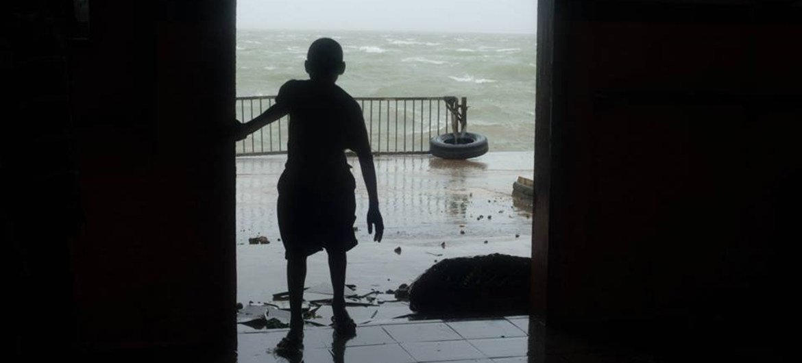 一位瓦努阿图儿童在热带气旋横扫该国时通过门口注视旋风肆虐的景象 （图片来源：儿基会）