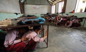 Students in Matatirtha, Nepal, which is in the process of being redeveloped to make the school more earthquake proof. As part of this process children are taught how to take shelter beneath their desks in case of an earthquake. Photo by Jim Holmes for AusAID.(13/2529)