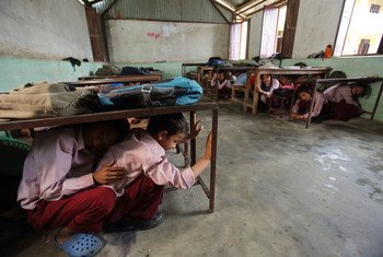 Students in Matatirtha, Nepal, which is in the process of being redeveloped to make the school more earthquake proof. As part of this process children are taught how to take shelter beneath their desks in case of an earthquake. Photo by Jim Holmes for Aus