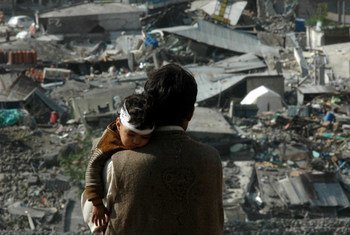 A father holds his injured child as he surveys the damage to the devastated city of Balakot, Pakistan, following an earthquake in 2005.