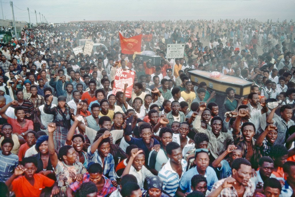 تظاهرة ضد التمييز العنصري في جنوب أفريقيا خلال جنازة لضحايا قتلوا من قبل الشرطة في ثمانينات القرن الماضي. صور الأمم المتحدة.