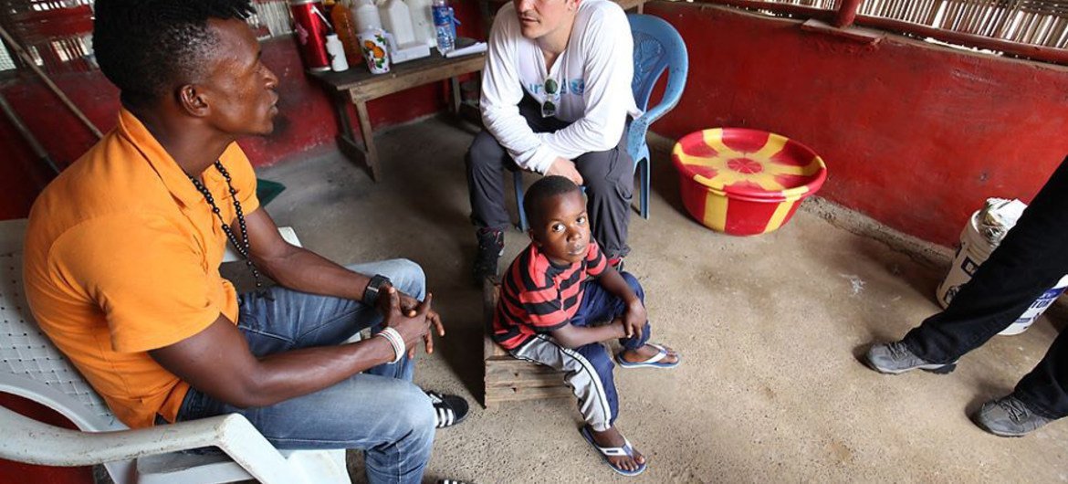 UNICEF Goodwill Ambassador Orlando Bloom (right) talks to a man who lost his wife, two step daughters and infant son to Ebola in Jene Wonde township in Grand Cape Mount County, Liberia.